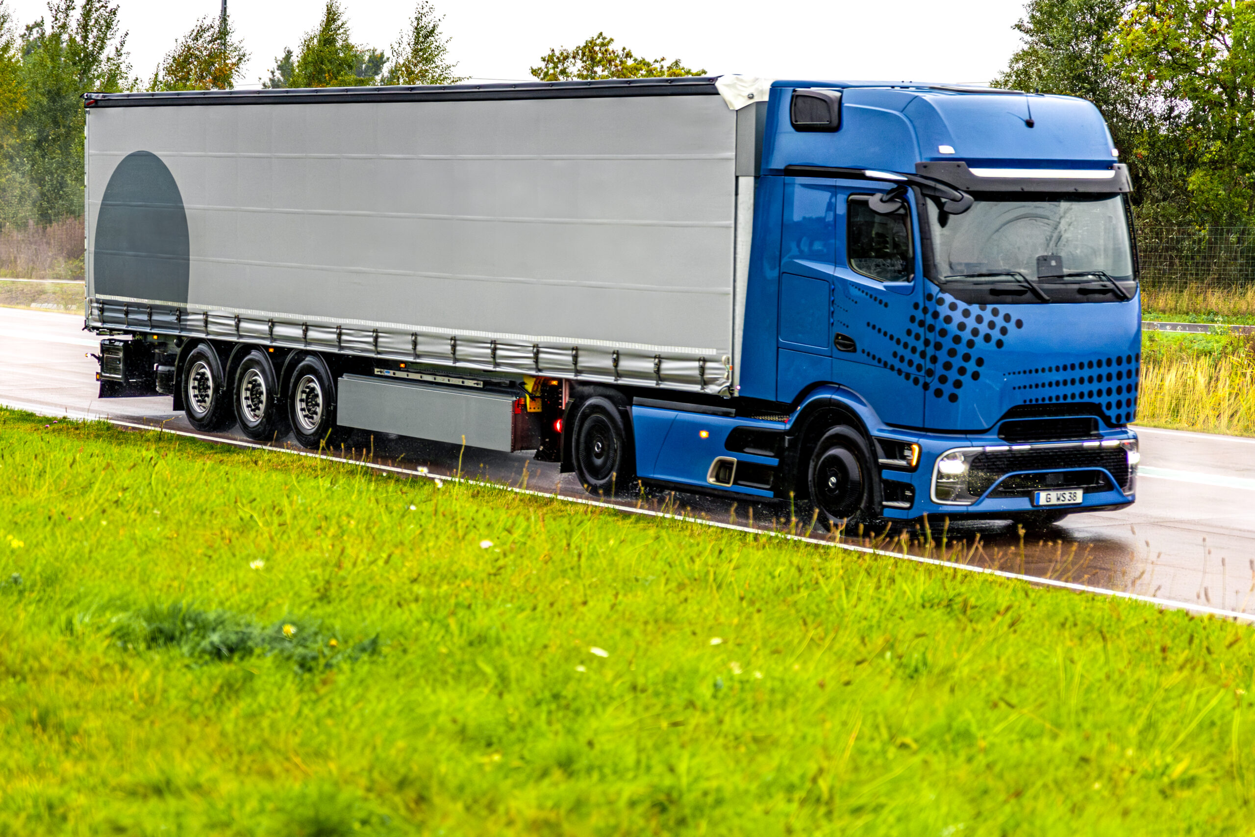 Modern blue truck on wet highway. Power and reliability in motion.